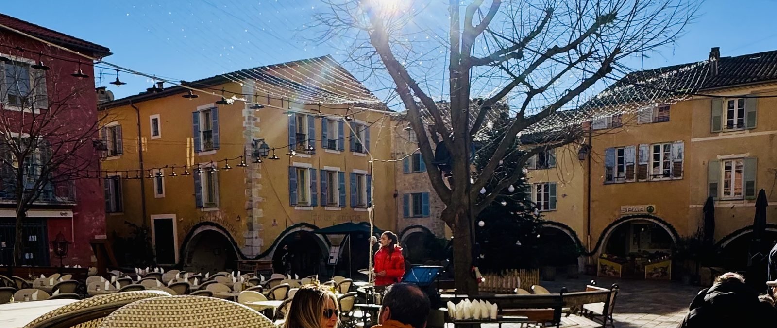 Place des Arcades in Valbonne, café tables, arcades, late-morning autumn light.